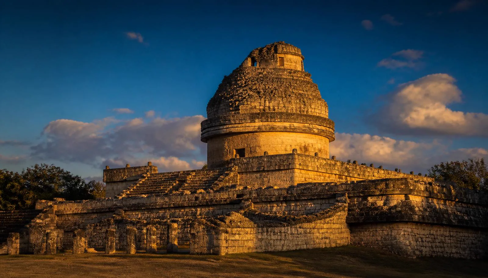 El Caracol observatory at Chichén Itzá, round Maya stone tower on a double rectangular platform against a deep blue Yucatán sky at golden hour, the ancient Maya astronomical observatory